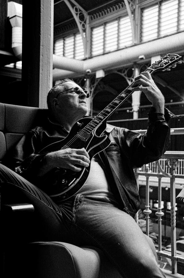 Candid black-and-white music portrait, guitarist in performance pose.