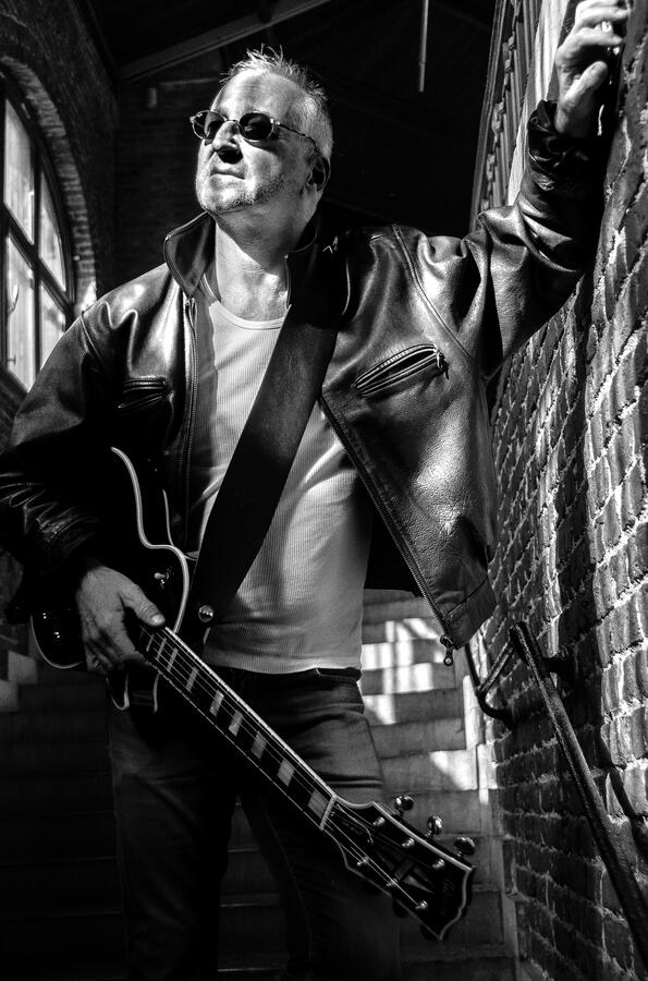 Black-and-white portrait of an independent rock musician with guitar.